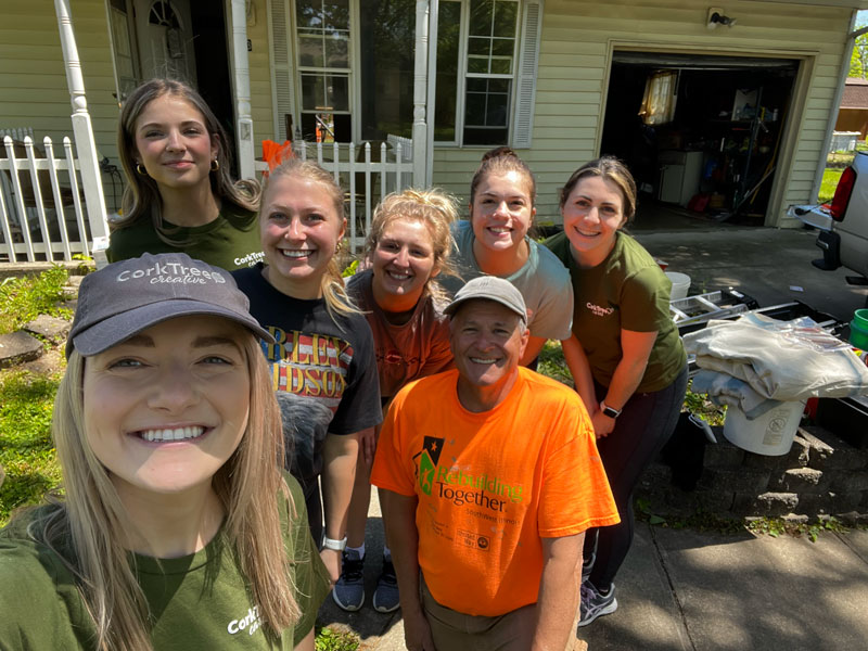 Group photo of the CorkTree Creative team in front of a Rebuilding Together project