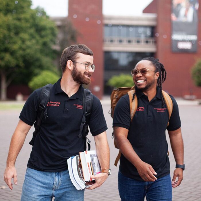 Two SIUE construction surveying students smile as they walk through campus
